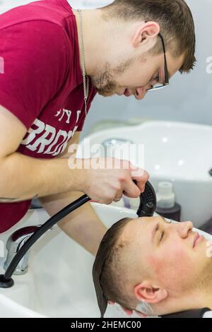 Männlicher Friseur spült Shampoo aus dem Haar des Kunden im Salon. Russland Moskau 17. November 2016. Stockfoto