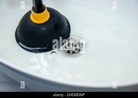 Konzept der Verstopfung mit einem Kolben. Verstopfte Rohre und Waschbecken im Badezimmer. Stockfoto