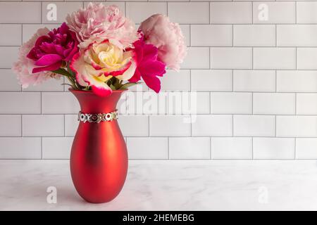 Rosa Rosen und Pfingstrosen in roter Vase zum Valentinstag mit Copy Space Stockfoto