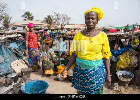 Frauen, die in der Nähe des Strandes an der Tanji-Küste in Gambia Fisch rauchen Stockfoto
