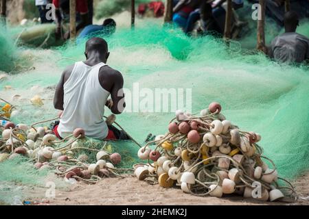 Mann repariert das Fischernetz am Tanji-Strand in Gambia Stockfoto