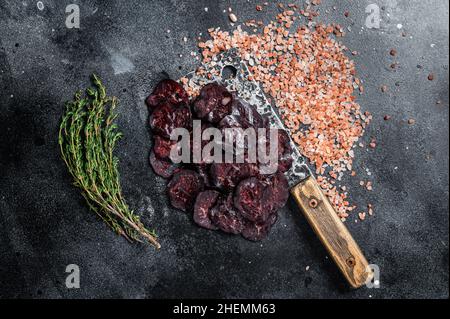 Trockene Salami-Wurst auf einem Metzgertisch. Schwarzer Hintergrund. Draufsicht Stockfoto