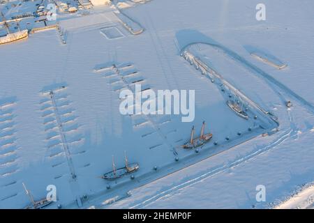 Ein leerer neuer Hafen und mehrere alte Fregatten unter dem Schnee an einem frostigen Winterabend Stockfoto