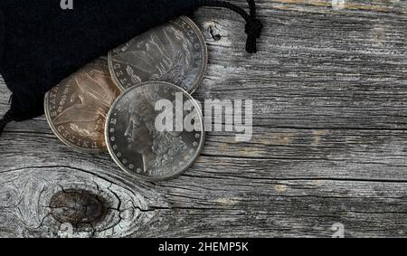 Vintage-Kollektion von US Morgan Silberdollar mit Patina-Finish, das aus der Tasche auf den rustikalen Holztisch verschüttet wurde Stockfoto