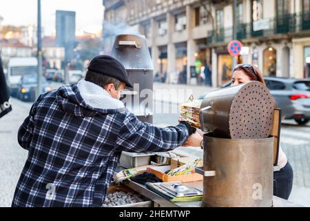 Porto, Portugal - 23. Oktober 2020: Straßenverkäufer von über Holzkohle gekochten heißen Kastanien, die an einem Herbsttag im historischen Stadtzentrum installiert wurden Stockfoto