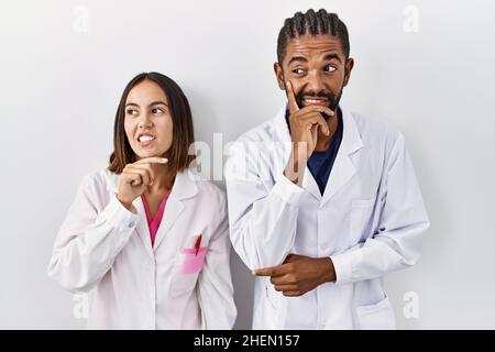Junge hispanische Ärzte stehen über weißem Hintergrund und denken besorgt über eine Frage, besorgt und nervös mit der Hand am Kinn Stockfoto