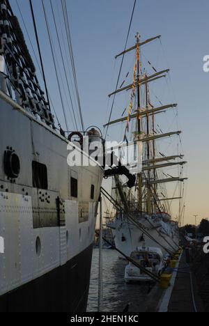 Hohe Schiffe vertäuten bei Sonnenuntergang in einem Hafen Stockfoto