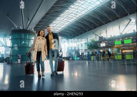 Schönes verliebtes Paar genießt eine gemeinsame Reise, geht durch die Abflug-Ankunftshalle, wartet auf Zoll- und Passkontrolle bei einem internationalen Stockfoto