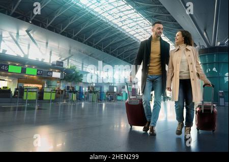 Schönes verliebtes Paar lächelt, lacht, genießt eine gemeinsame Reise, geht durch die Abflug-Ankunftshalle, wartet auf Zoll- und Passkontrolle bei t Stockfoto