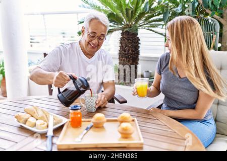 Das hispanische Paar mittleren Alters lächelte und freute sich beim Frühstück auf der Terrasse. Stockfoto