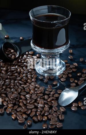 Helsinki / Finnland - 11. JANUAR 2022: Eine Tasse frischen Kaffees umgeben von Kaffeebohnen vor dunklem Hintergrund. Stockfoto