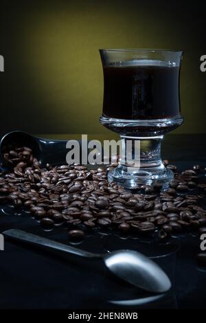 Helsinki / Finnland - 11. JANUAR 2022: Eine Tasse frischen Kaffees umgeben von Kaffeebohnen vor dunklem Hintergrund. Stockfoto