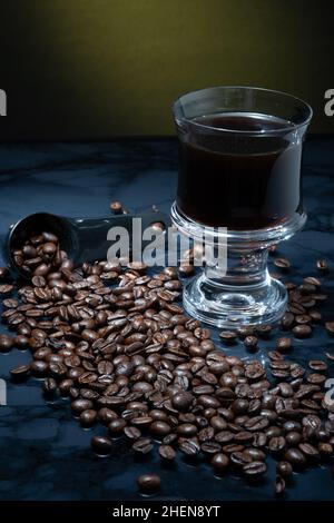 Helsinki / Finnland - 11. JANUAR 2022: Eine Tasse frischen Kaffees umgeben von Kaffeebohnen vor dunklem Hintergrund. Stockfoto