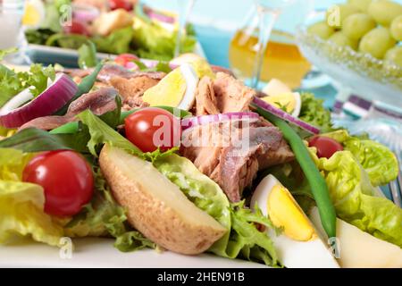 Nicoise Salat Nahaufnahme mit Trauben und Weinglas auf dem Hintergrund Stockfoto