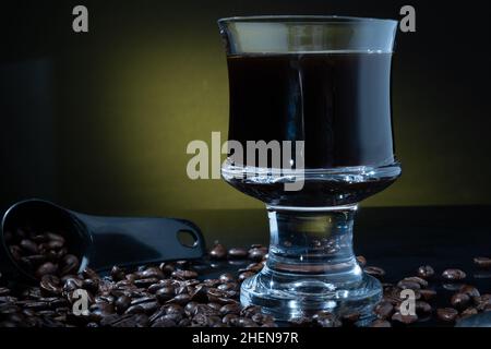 Helsinki / Finnland - 11. JANUAR 2022: Eine Tasse frischen Kaffees umgeben von Kaffeebohnen vor dunklem Hintergrund. Stockfoto