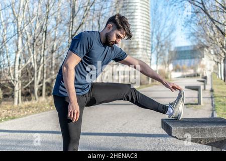 Junger Mann im Park, der sich die Beine streckt Stockfoto