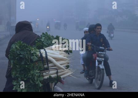 Lahore. Pakistan, 11/10/2022, pakistanische Bürger, Studenten unterwegs während eines kalten und dichten nebligen Morgens in Lahore. Pakistanische Bewohner und Pendler sind aufgrund der plötzlichen Schicht dichten Smogs, die Probleme bei der Atmung, der Sicht verursacht und auch den reibungslosen Verkehrsfluss behindert, mehr besorgt als überrascht. Die Bewohner von Lahore erwachten am Donnerstag zu einer dichten Smogdecke auf, die die Sicht der Pendler verringerte und mehrere Beschwerden über Atembeschwerden und psychische Qualen auflöste. (Foto von Rana Sajid Hussain/Pacific Press) Stockfoto