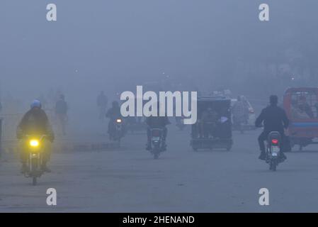 Lahore. Pakistan, 11/10/2022, pakistanische Bürger, Studenten unterwegs während eines kalten und dichten nebligen Morgens in Lahore. Pakistanische Bewohner und Pendler sind aufgrund der plötzlichen Schicht dichten Smogs, die Probleme bei der Atmung, der Sicht verursacht und auch den reibungslosen Verkehrsfluss behindert, mehr besorgt als überrascht. Die Bewohner von Lahore erwachten am Donnerstag zu einer dichten Smogdecke auf, die die Sicht der Pendler verringerte und mehrere Beschwerden über Atembeschwerden und psychische Qualen auflöste. (Foto von Rana Sajid Hussain/Pacific Press) Stockfoto