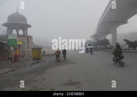 Lahore, Punjab, Pakistan. 11th Januar 2022. Pakistanische Bürger, Studenten, die während eines kalten und dichten nebligen Morgens in Lahore unterwegs sind. Pakistanische Bewohner und Pendler sind aufgrund der plötzlichen Schicht dichten Smogs, die Probleme bei der Atmung, der Sicht verursacht und auch den reibungslosen Verkehrsfluss behindert, mehr besorgt als überrascht. Die Bewohner von Lahore erwachten am Donnerstag zu einer dichten Smogdecke auf, die die Sicht der Pendler verringerte und mehrere Beschwerden über Atembeschwerden und psychische Qualen auflöste. (Bild: © Rana Sajid Hussain/Pacific Press via ZUMA Press Wire) Stockfoto