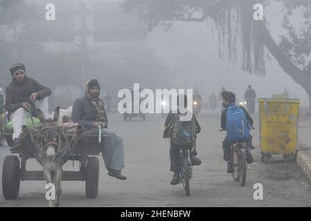 Lahore, Punjab, Pakistan. 11th Januar 2022. Pakistanische Bürger, Studenten, die während eines kalten und dichten nebligen Morgens in Lahore unterwegs sind. Pakistanische Bewohner und Pendler sind aufgrund der plötzlichen Schicht dichten Smogs, die Probleme bei der Atmung, der Sicht verursacht und auch den reibungslosen Verkehrsfluss behindert, mehr besorgt als überrascht. Die Bewohner von Lahore erwachten am Donnerstag zu einer dichten Smogdecke auf, die die Sicht der Pendler verringerte und mehrere Beschwerden über Atembeschwerden und psychische Qualen auflöste. (Bild: © Rana Sajid Hussain/Pacific Press via ZUMA Press Wire) Stockfoto