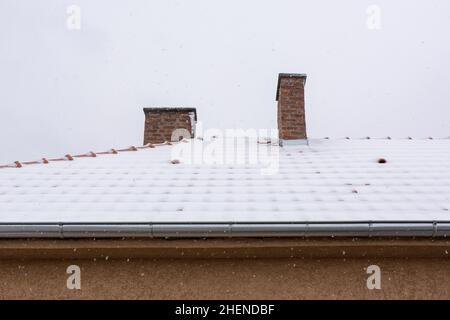 Dach mit Kaminen auf dem Haus mit Schnee bedeckt an einem kalten Wintermorgen Stockfoto