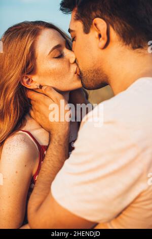 Nahaufnahme eines Paares, das sich in einem sonnigen Weizenfeld küsst. Wunderschöne Sommerlandschaft. Landschaft auf dem Land. Familienwochenende. Weizenfeld. Stockfoto