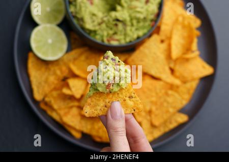 Draufsicht auf die Frau, die Tortilla-Chips oder Nachos mit leckeren Guacamole Dip hält Stockfoto