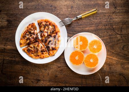 Köstliche italienische Pizzas auf einem Holztisch mit Orange Stockfoto