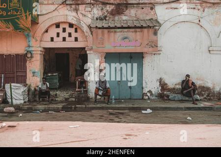 Dschibuti, Dschibuti - 21. Mai 2021: Drei Männer aus Dschibuti sitzen im Schatten vor einem afrikanischen Gebäude. Redaktionelle Aufnahme in Dschibuti Stockfoto