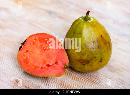 Ganze und halbierte tropische Apfelguavas auf Holzhintergrund Stockfoto