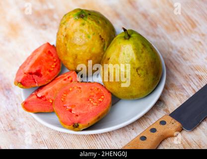 Ganze und halbierte tropische Apfelguavas auf Holzhintergrund Stockfoto