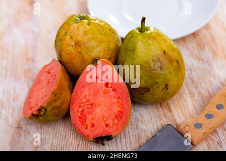 Ganze und halbierte tropische Apfelguavas auf Holzhintergrund Stockfoto