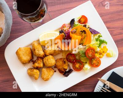 Eingelegter Dogfish mit gehacktem Gemüse auf weißem Teller Stockfoto