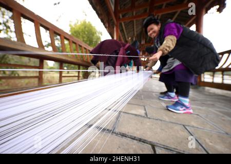 QIANDONGNAN, CHINA - 11. JANUAR 2022 - Dorfbewohner arrangieren Garn für das Weben traditioneller ethnischer Kleidungsstücke aus Miao in der südöstlichen Provinz Guizhou, Chin Stockfoto