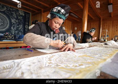 QIANDONGNAN, CHINA - 11. JANUAR 2022 - Miao Handwerkswerkstatt näht Batikbekleidungsprodukte im Südosten der Provinz Guizhou, China, 11. Januar 2022. Stockfoto