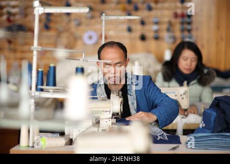 QIANDONGNAN, CHINA - 11. JANUAR 2022 - Miao Handwerkswerkstatt näht Batikbekleidungsprodukte im Südosten der Provinz Guizhou, China, 11. Januar 2022. Stockfoto