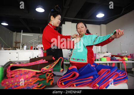 QIANDONGNAN, CHINA - 11. JANUAR 2022 - umgesiedelte Menschen überprüfen die Qualität der traditionellen Miao-Kleidung in Qiandongnan, Provinz Guizhou, China, Janua Stockfoto