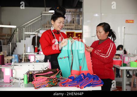 QIANDONGNAN, CHINA - 11. JANUAR 2022 - umgesiedelte Menschen überprüfen die Qualität der traditionellen Miao-Kleidung in Qiandongnan, Provinz Guizhou, China, Janua Stockfoto