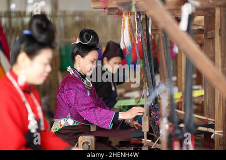 QIANDONGNAN, CHINA - 11. JANUAR 2022 - umgesiedelte Menschen weben traditionelle Miao-Bekleidungsstoffe in der südöstlichen Provinz Guizhou, China, 11. Januar 2022 Stockfoto