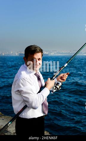 Ein türkischer Mann, der von der Uferpromenade entlang des Goldenen Horns in Istanbul, Türkei, fischt. Stockfoto