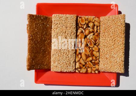 Leckere Peanut Chikki, Sesamsamen Chiki, Rajgira oder Amaranth Chikky und zerkleinerte Peanut Chikkis. Sankranti spezielle traditionelle Süßigkeiten verschiedene Töpfe Stockfoto