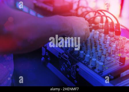 Hände eines djs, der die Musik auf einem Mixer steuert Stockfoto