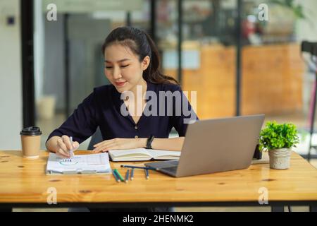 Schöne junge weibliche College-Studentin oder Finanzhochschülerin, die ihre Finanzaufgaben im Café macht. Stockfoto