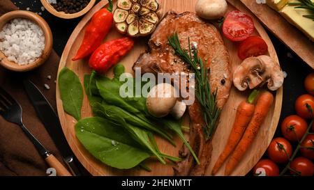 Saftig gegrilltes Schweinekotelett oder Tomahawk Steak mit spezieller Würze servieren mit gesundem gegrilltem Gemüse. Draufsicht, oben Stockfoto