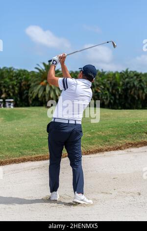 Golfspieler spielt ab. Mann, der Golfball vom Abschlagkasten im Golf Club in Miami, Florida, trifft. Golftour. Outdoor-Sportereignis. Stockfoto