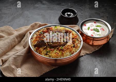 Fisch Biriyani, südindischer Art Fisch biriyani traditionell in einem Messinggefäß mit Raitha als Beilage angeordnet. Stockfoto