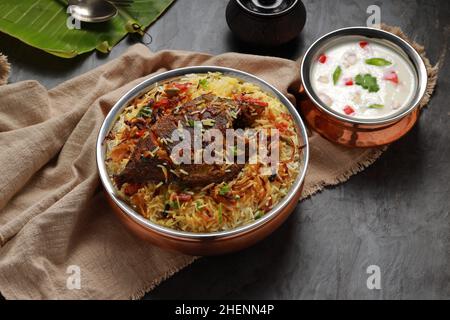 Fisch Biriyani, südindischer Art Fisch biriyani traditionell in einem Messinggefäß mit Raitha als Beilage angeordnet. Stockfoto