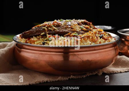 Fisch Biriyani, südindischer Art Fisch biriyani traditionell in einem Messinggefäß mit Raitha als Beilage angeordnet. Stockfoto