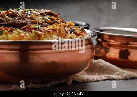 Fisch Biriyani, südindischer Art Fisch biriyani traditionell in einem Messinggefäß mit Raitha als Beilage angeordnet. Stockfoto