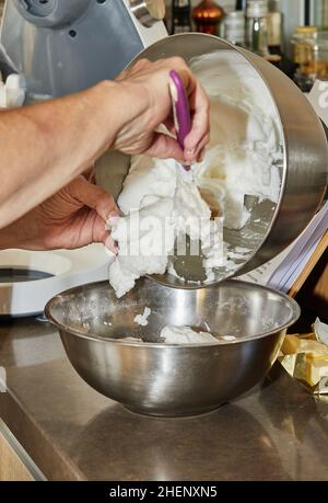 Der Koch gibt das geschlagene Eiweiß in eine Pie-Schüssel Stockfoto